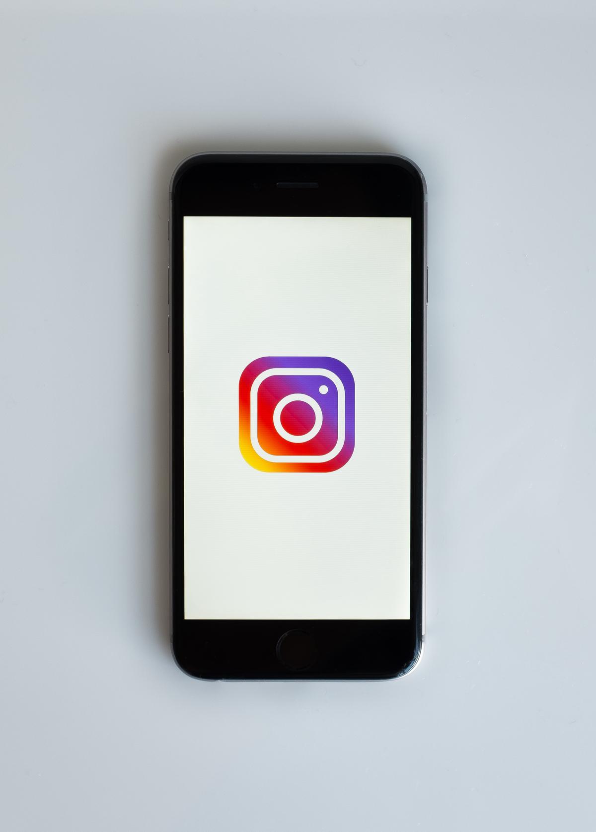 A person holding a smartphone with the Instagram logo displayed on the screen, representing earning money from Instagram